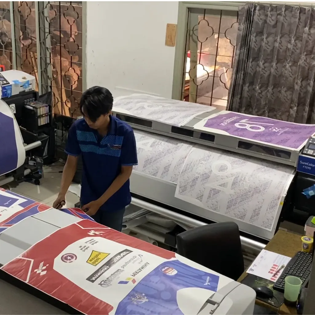 Pekerja maklon sedang memeriksa kualitas cetakan digital untuk produksi sesuai spesifikasi kontrak.