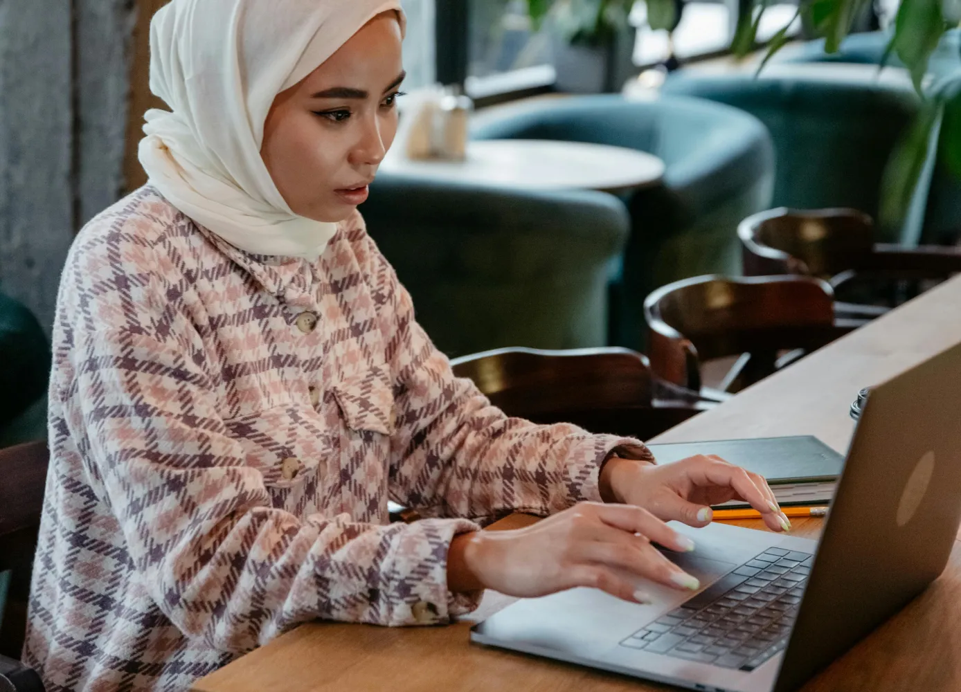 Seorang wanita menggunakan laptop untuk mengelola bisnis hijab secara digital.