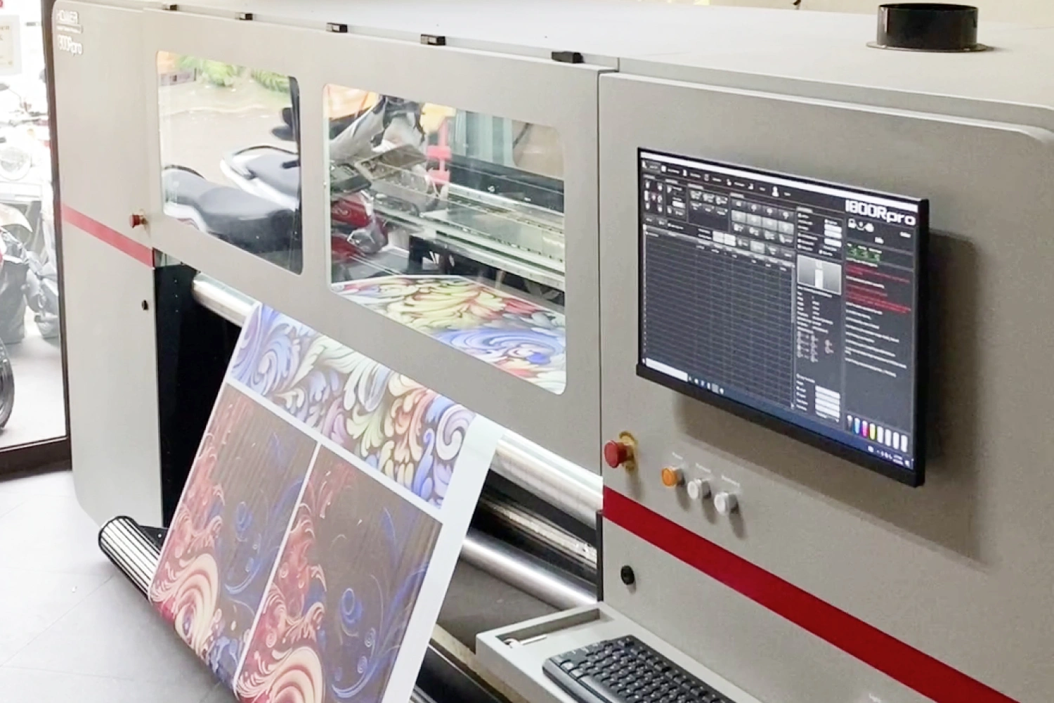 Mesin digital printing sedang mencetak produk fashion dalam jumlah massal.